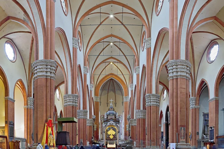 Grand church interior with tall red columns, arches and central altar inside Basilica of San Petronio Bologna