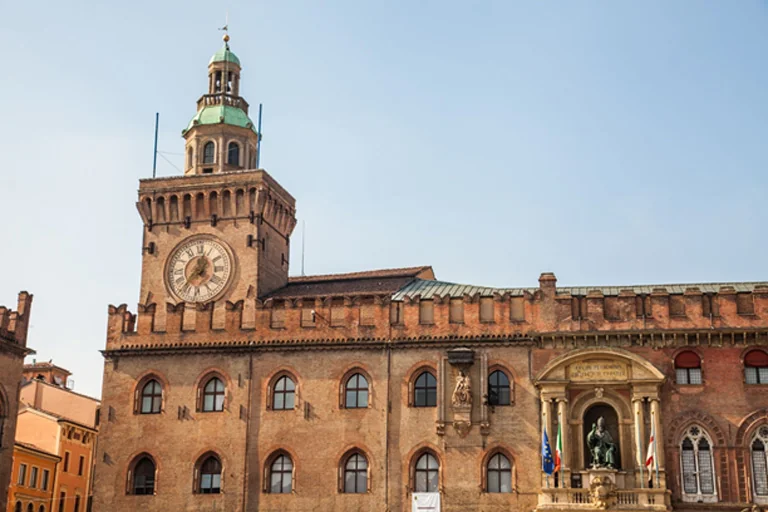 Historic Palazzo d’Accursio building with clock tower and brick facade located in Piazza Maggiore Bologna Italy