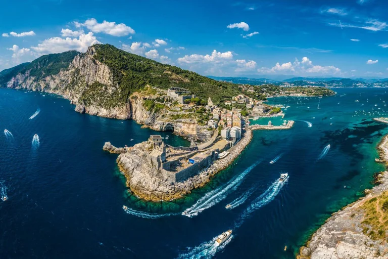 Aerial view of Liguria's dramatic coastline, turquoise sea, and colorful Italian Riviera villages in summer.